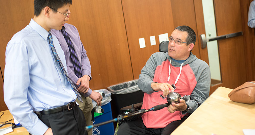 Undergraduate Mathew Li talks to Mike Thompson as he tries out the Bass Grabber.
