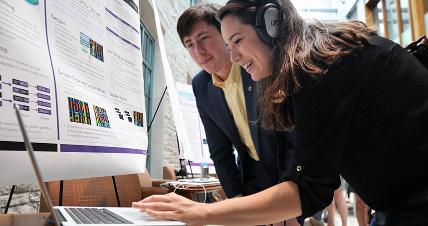 A visitor listens to the music that graduate student Connor Bain (left) composed with NetLogo.