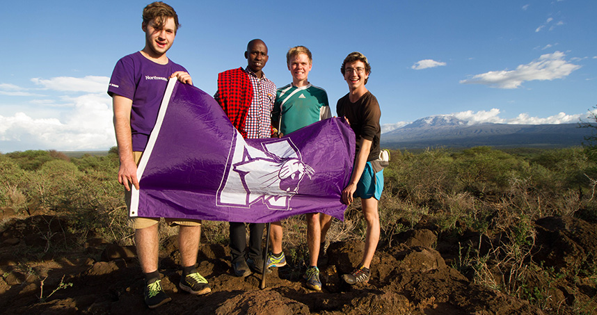 EWB-NU students wave a Northwestern flag in front of Mount Kilimanjaro.