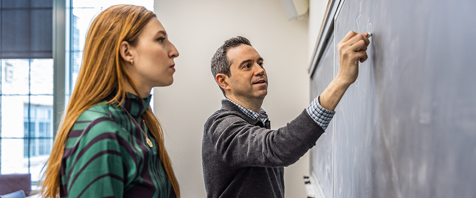 Prof Daniel Abrams and student working on problem at chalkboard