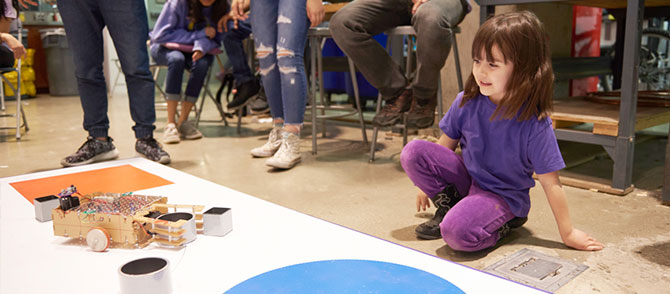 A small visitor watches a robot during the competition
