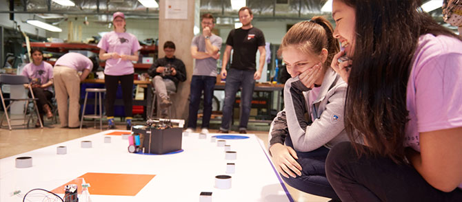 Students watch their robot compete in the arena.