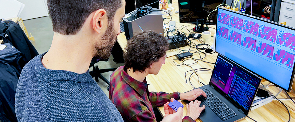 Two people in lab working at desk with computers