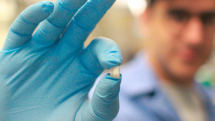 Gloved hand holding small sensor