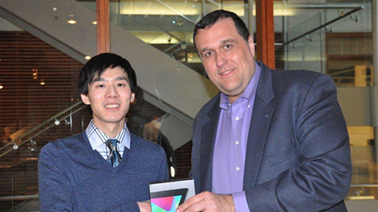 Mark Werwath, director of Northwestern's Master of Engineering Management (MEM) program, presents a Nexus 7 Wifi Tablet to competition winner James Du.