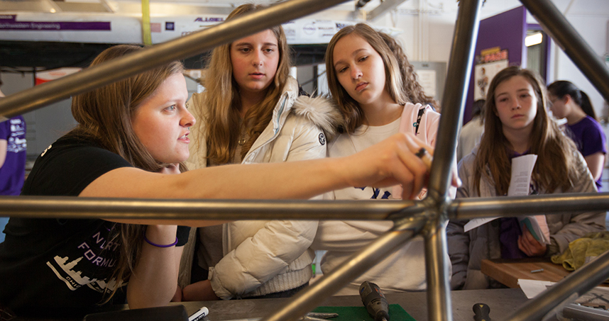 Undergraduate Tiernan Murrell (left) shows participants what it takes to build a car.