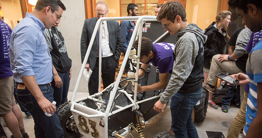Team adviser Michael Beltran (left) takes a look at the Baja car.