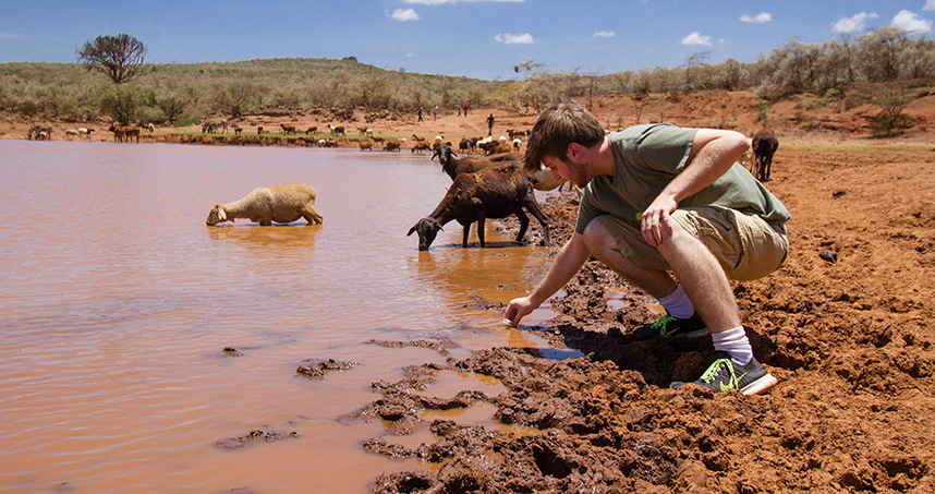 A student collects pond water from which Maasai villagers and animals drink.
