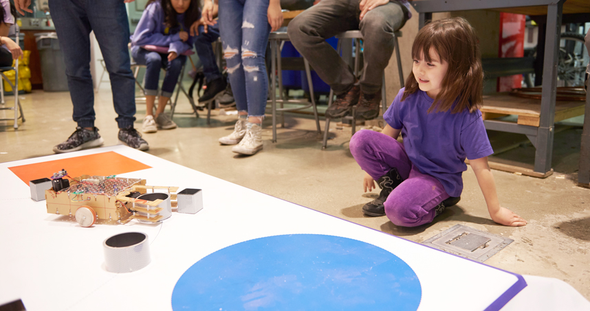 A small visitor watches a robot during the competition
