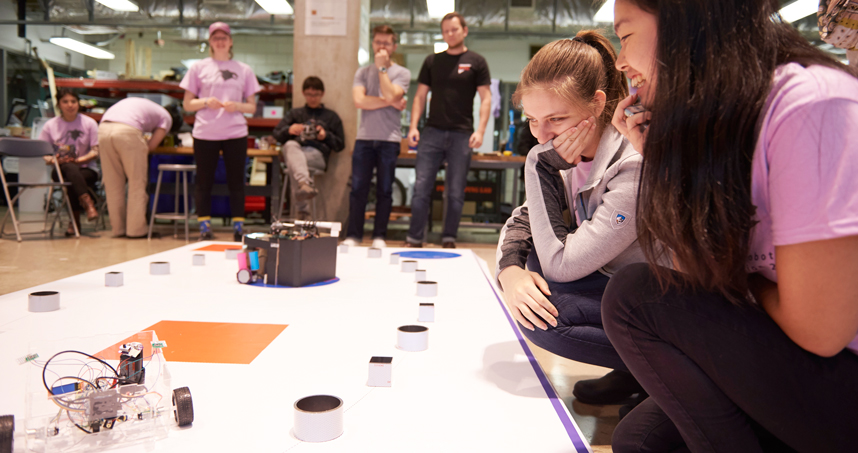Students watch their robot compete in the arena.