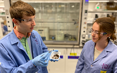 PhD student Benjamin Shindel and undergraduate Caroline Harms examine a sample of the nanoparticle-coated sponge.