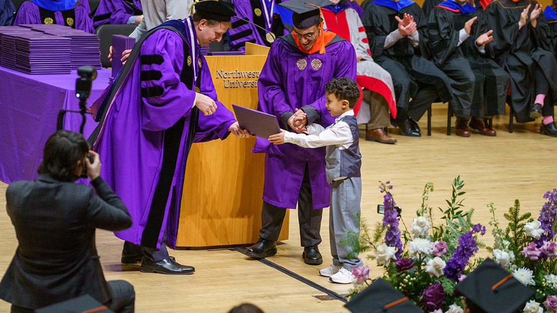 A graduate and a youngster receive a diploma during Saturday's event.