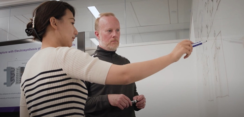 Rong Xia (left) and Ted Sargent (right) discuss the project on a whiteboard.
