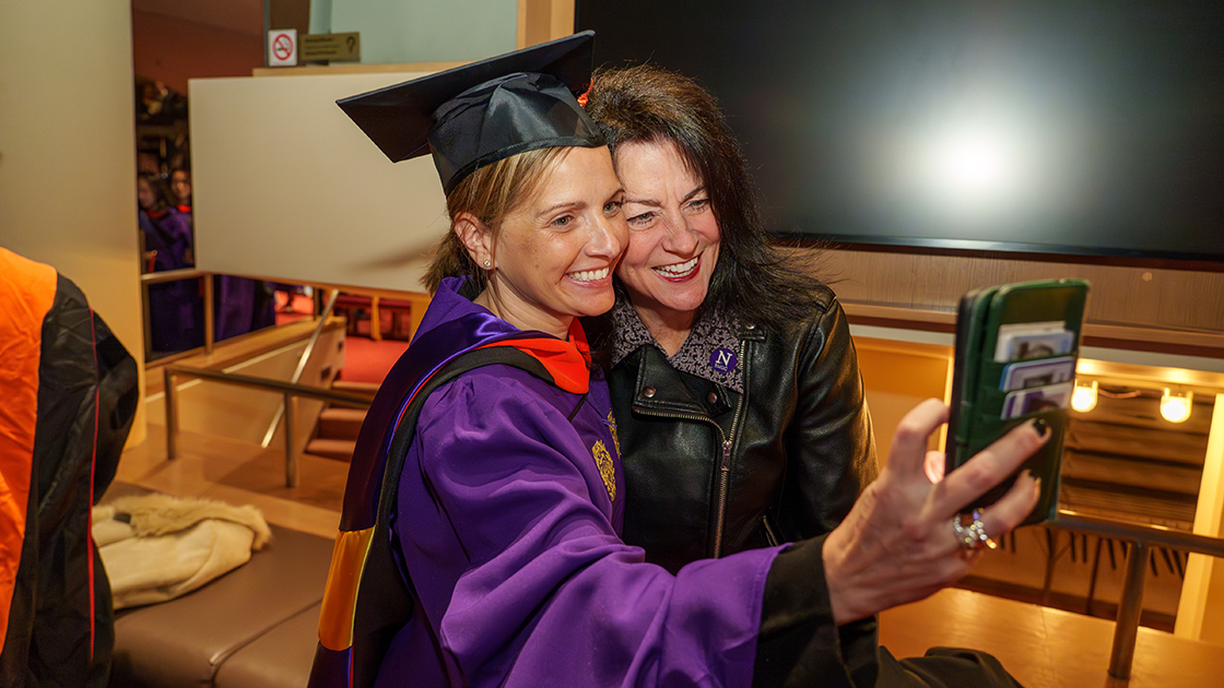 A graduate and a supporter take a selfie after the ceremony.