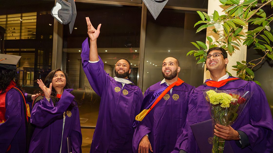 Inside the Pick-Staiger Concert Hall lobby, graduates toss their caps into the air.