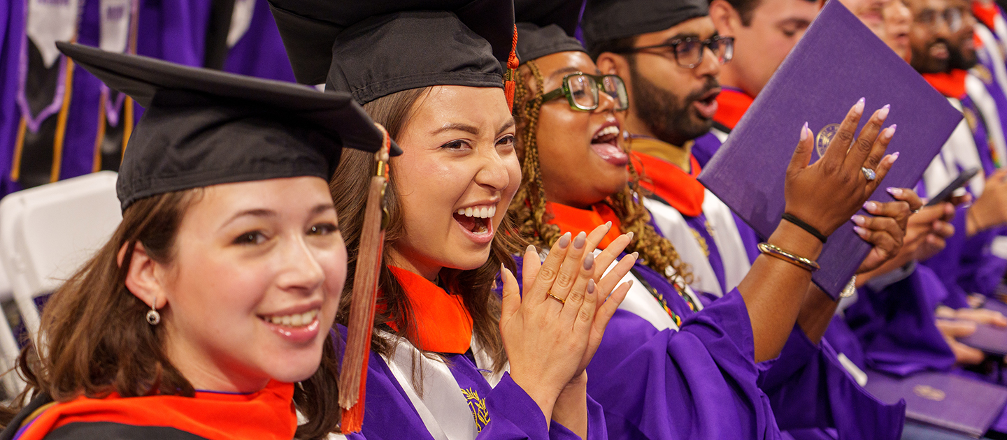A group of graduates celebrates during the PhD Hooding and Master's Degree Recognition Ceremony.