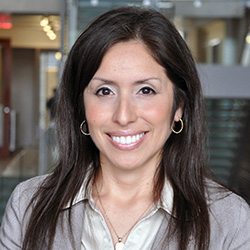 a light skinned woman with dark brown long hair smiles at the camera