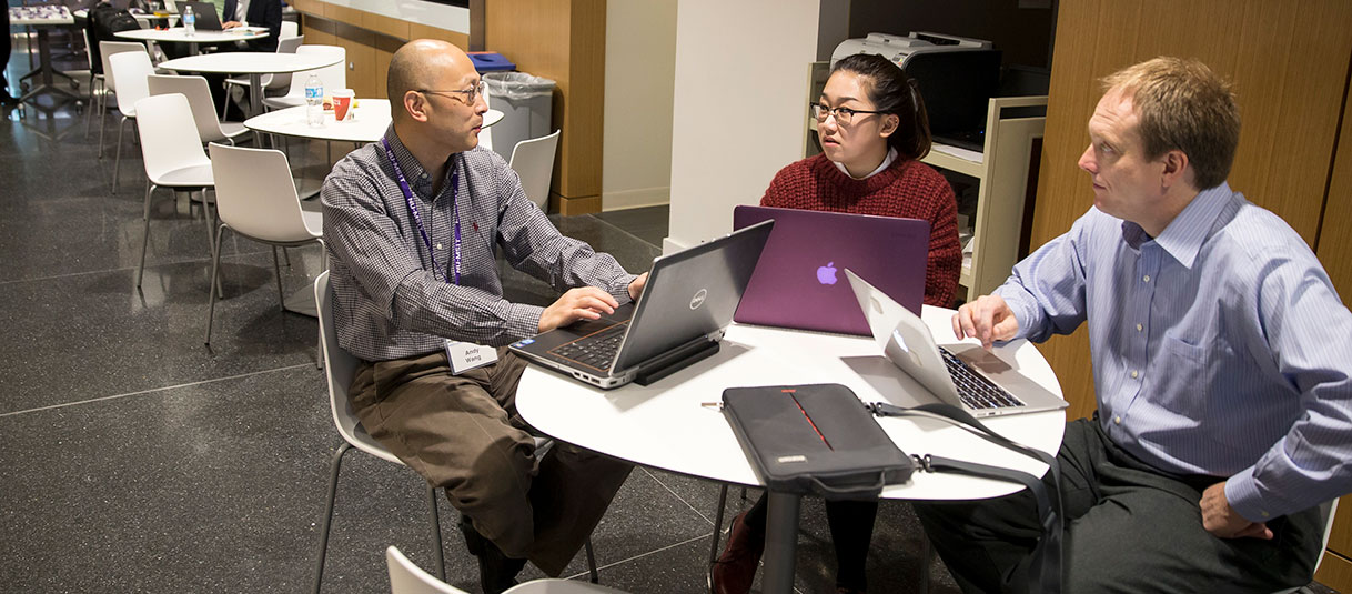 MSIT Students sitting at a table with their laptops in conversation