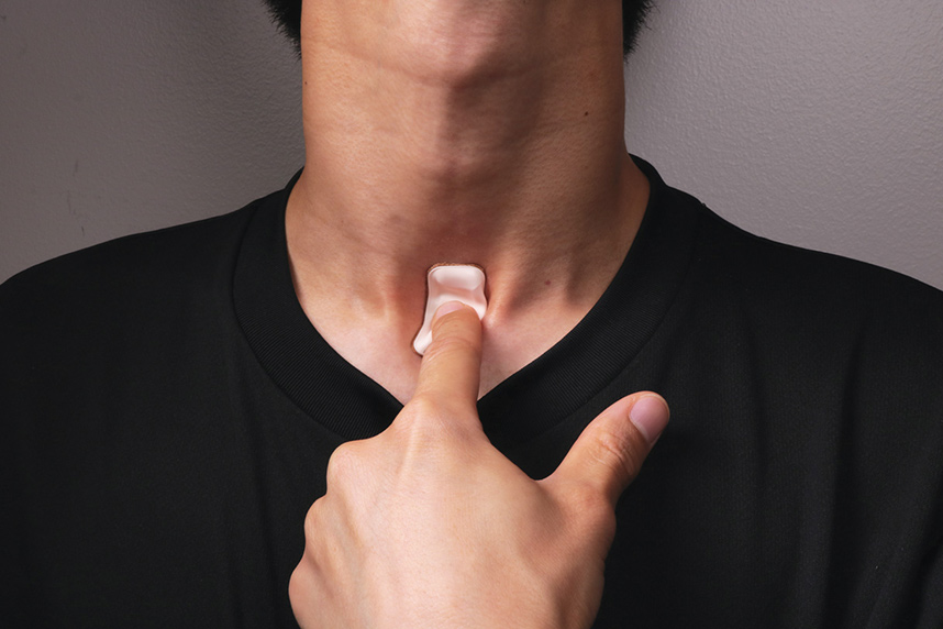 The soft, flexible wireless device sits just below the suprasternal notch at the base of the throat.