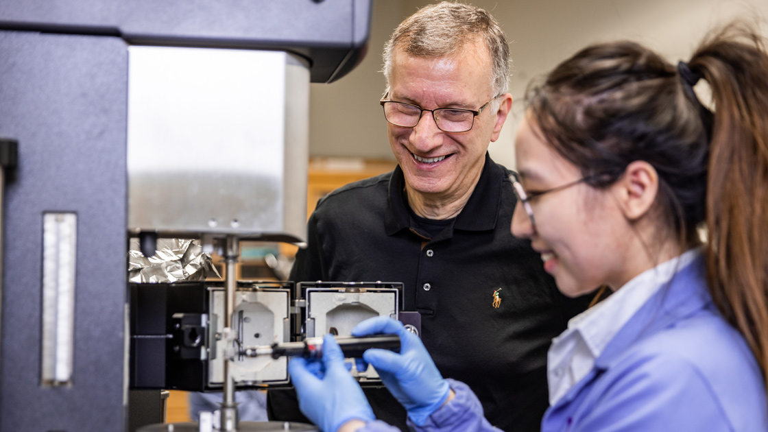 John Torkelson and a student adjusting a machine together