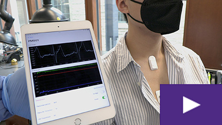 person wearing heart monitor and showing readout on tablet display