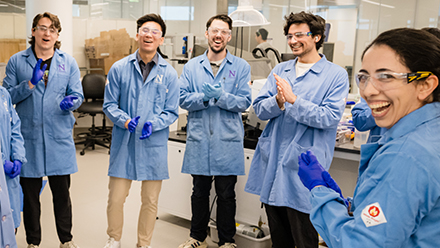 Students in lab coats in a lab.