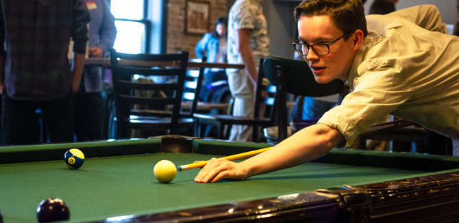 A student plays pool at the Firehouse Grill.