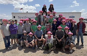 Group of students in pink cowboy hats smiling at camera