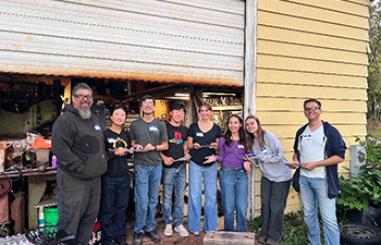 Members of the Bladesmithing Club standing in front of a workshop