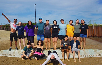 Concrete Canoe team standing on a canoe at the beach