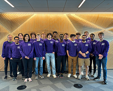Group of students standing together wearing purple shirts