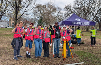 Students outdoors with safety vests and survey equipment